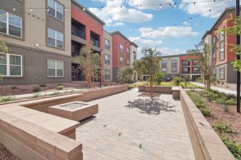 An outdoor area with benches and trees in front of an apartment building